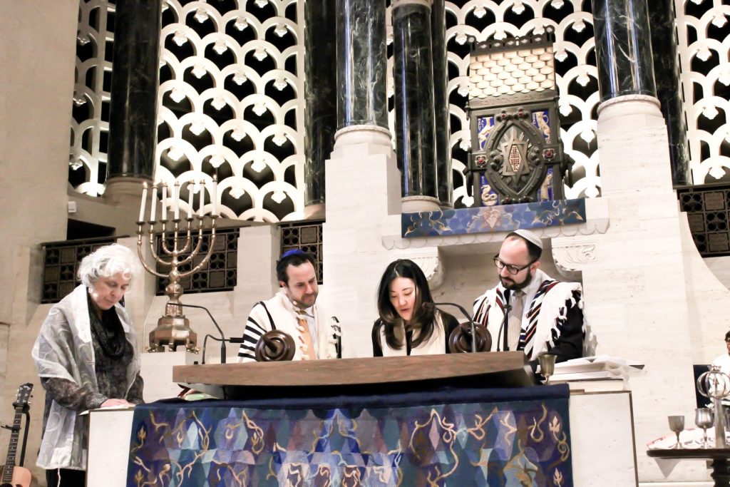 With the support of a rabbi and two cantors, reading from Torah